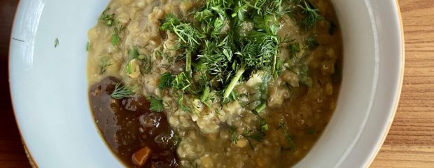 from above white bowl with yellow dhal topped with red chutney and a sprinling of green herbs