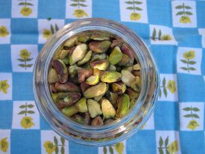 glass jar of hulled pistachio nuts on patterned table cloth