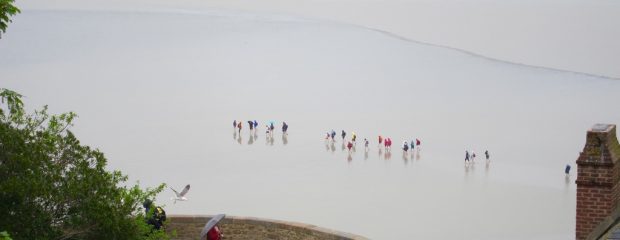 aerial view of grey beach with a line of children in multicoloured coats France