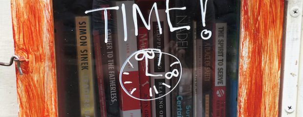street library orange painted wood around a glass window with read a book you've got time