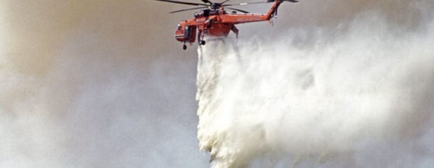 red helicopter against a dark sky dropping white powder on trees text reads naturopathic bushfire support for fire trauma and smoke exposure gillstannard dot com dot au
