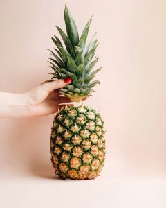 upright pineapple with hand holding the crown