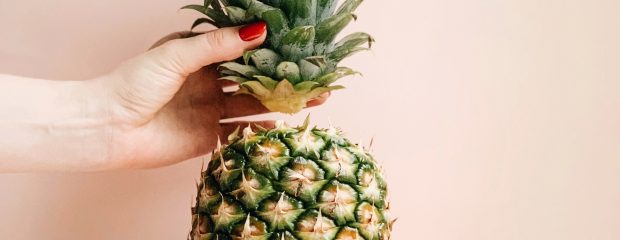 upright pineapple with hand holding the crown