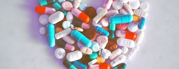 different coloured pills and capsules arranged in a heart shape