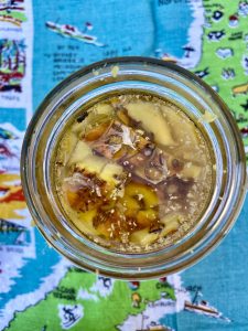 aerial view glass jar of pineapple skins covered in liquid of an vintage tea towel map of new zealand