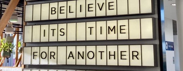 Black letters on a white digital board read 